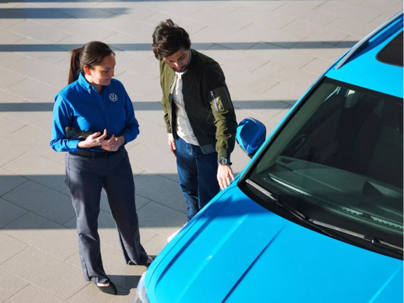 Hombre admirando el vehículo Volkswagen con un técnico certificado.