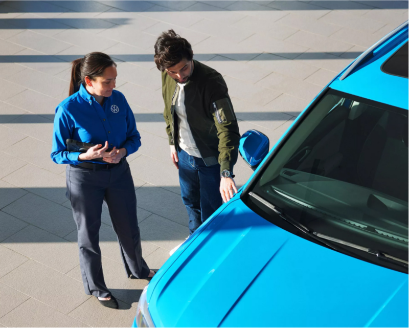 Man admiring Volkswagen vehicle with a certified technician.