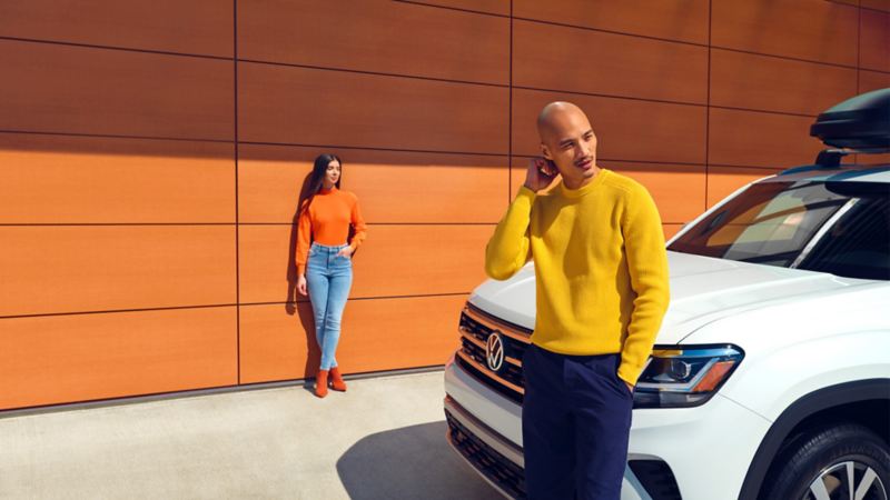 Un homme et une femme se tiennent debout à côté d’un Atlas Cross Sport 2022 de VW.