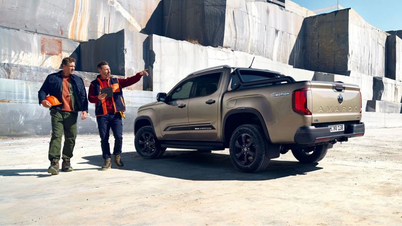 Zwei Männer gehen an einem parkendem VW Amarok PanAmericana vorbei.