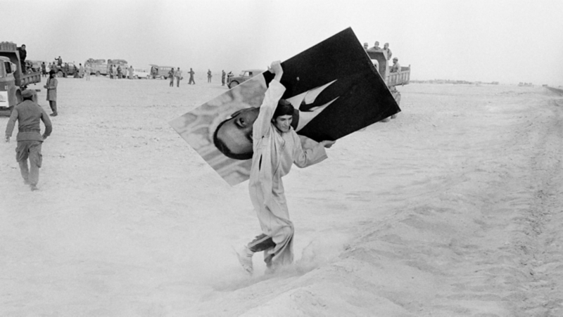White VW Golf eHybrid charging and parking sideways next to cafe. Two Men next to the car
