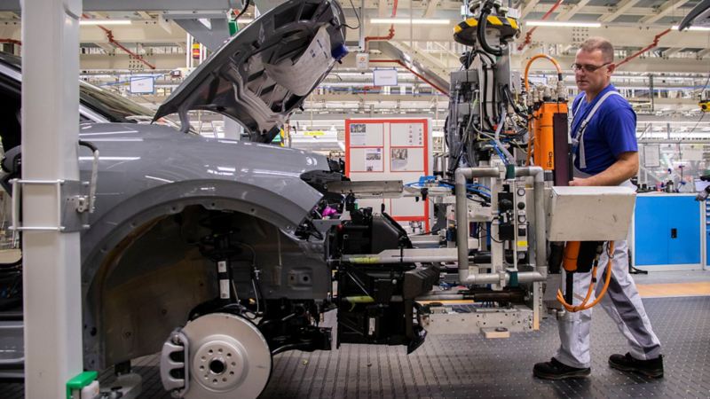 Eine Volkswagen Mitarbeiterin hält ein Bedien-Display eines Montage-Roboters in der Hand