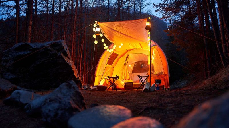 Ein Zelt mit Lichterketten im Wald sorgt für gemütliches Licht 