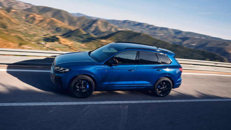 A Touareg R eHybrid from Volkswagen R drives along a country road in the mountains