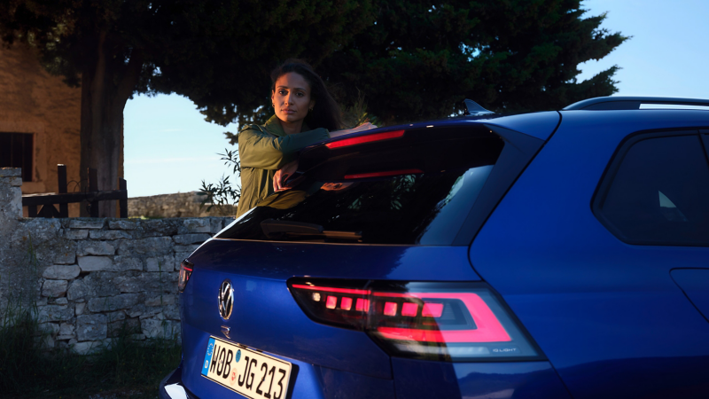 Une femme est appuyée contre le toit d’une VW Golf R Variant 
