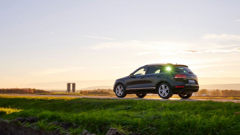 Schwarzer VW Touareg 2 fährt bei Sonnenuntergang durch eine Landschaft