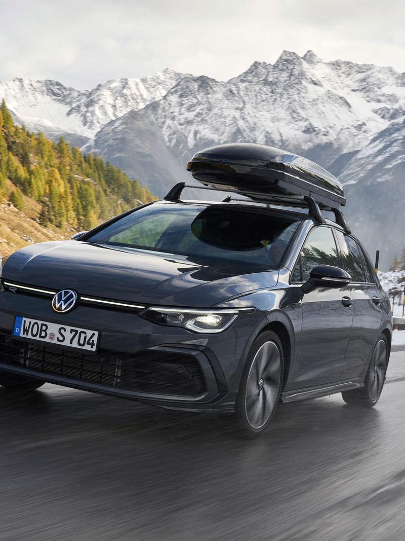 A VW Golf R-Line with complete all-season wheels drives through a snowy mountain landscape