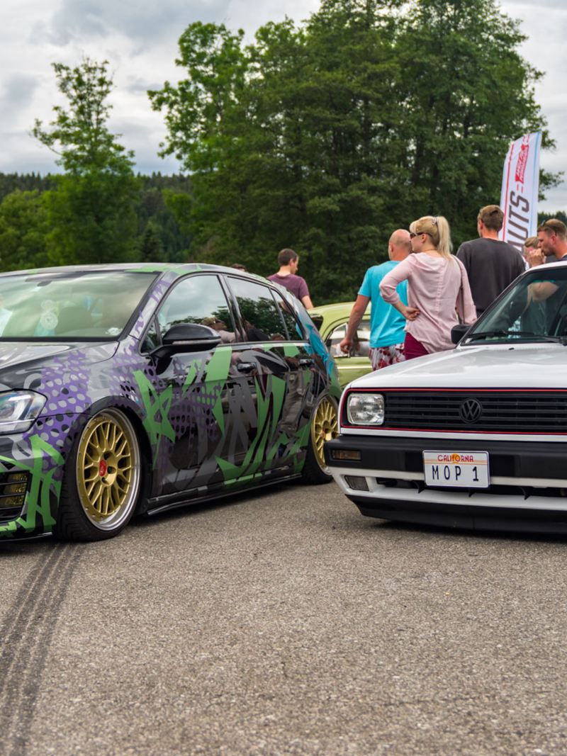 Two VW GTI models at a GTI Fanfest with visitors in the background