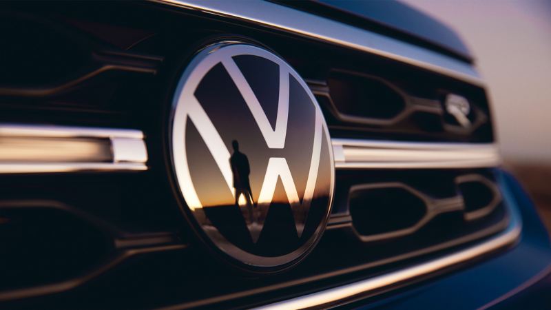 Ein Mensch spiegelt sich in dem VW Logo an einem R-Modell