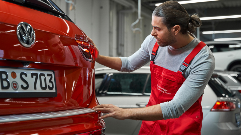 Servicemitarbeiter vom Volkswagen Economy Service prüft Rücklichter eines VW Autos