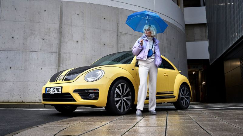 Eine Frau und ihr gebrauchter VW Beetle der Kompaktklasse