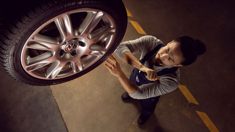 Un empleado del servicio técnico de Volkswagen revisa un neumático Volkswagen en un taller