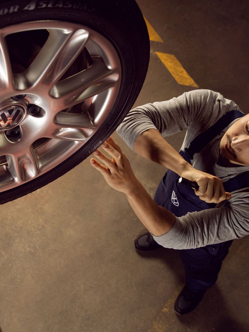 Un empleado del servicio técnico de Volkswagen revisa un neumático Volkswagen en un taller