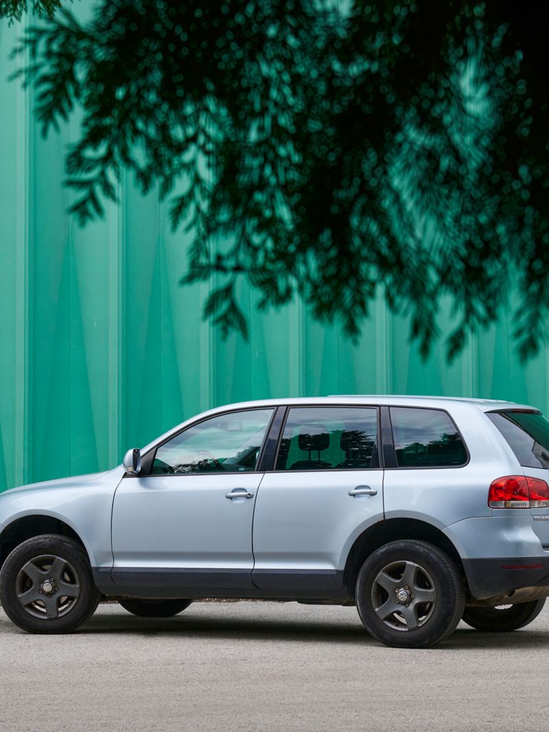 El versátil VW Touareg 1 está aparcado frente a un edificio turquesa 
