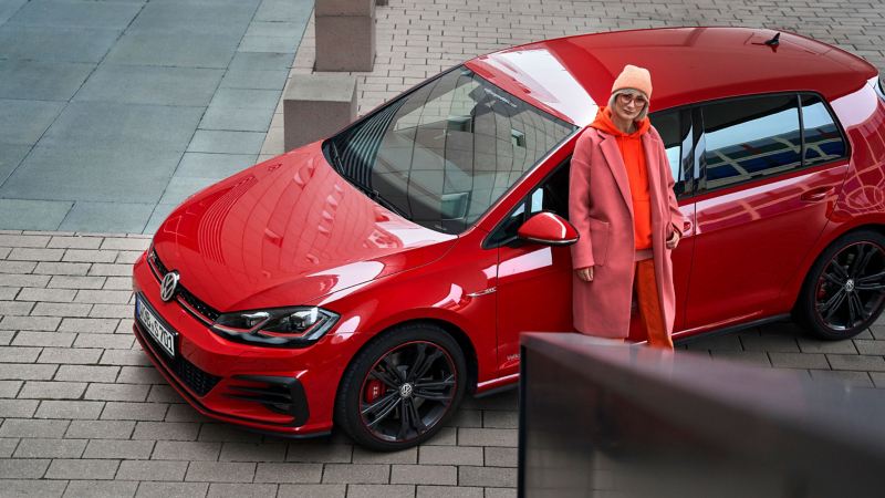 Une femme et sa VW Golf 7 de couleur rouge