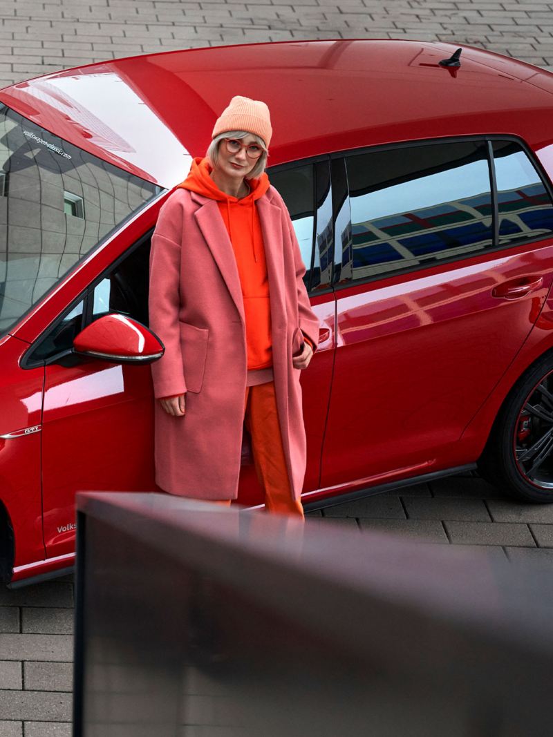 Une femme et sa VW Golf 7 de couleur rouge