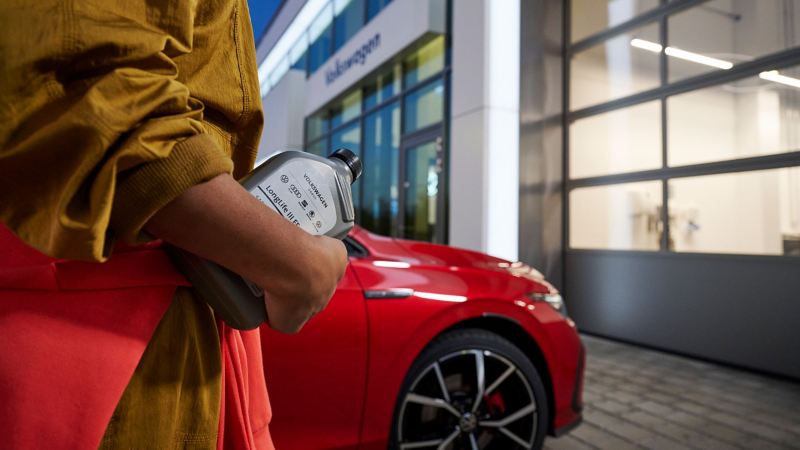 Someone holding a bottle of LongLife III FE engine oil, a VW car in the background