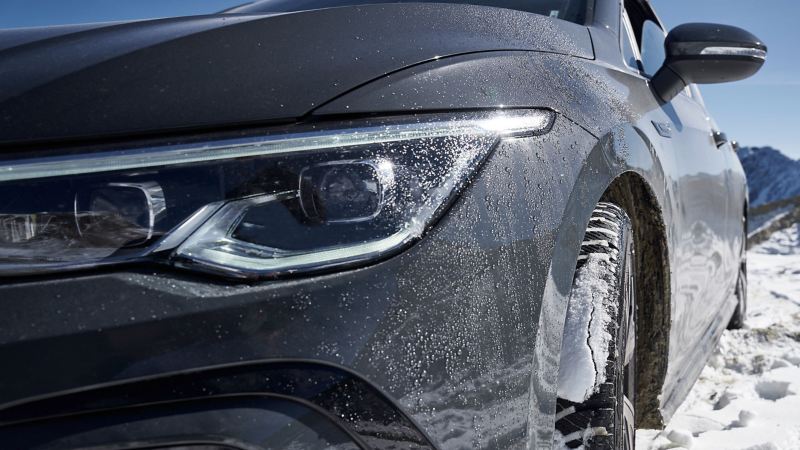 Ein VW Auto im Schnee – Fokus auf den linken Scheinwerfer