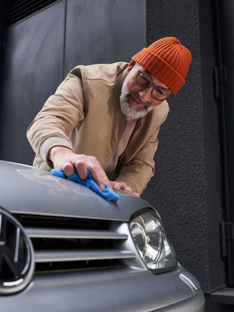 Ein Mann reinigt die Motorhaube seines Golf 4 Vorgängermodells