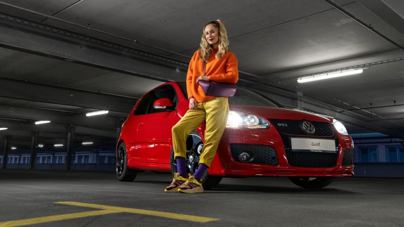 A woman leans against her VW Golf 5 with VW accessories