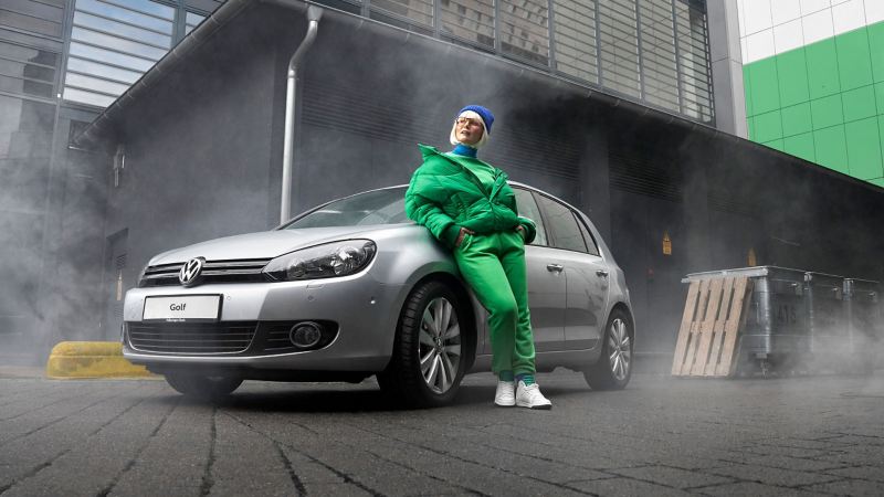 A woman leans against her VW Golf 6 with VW accessories