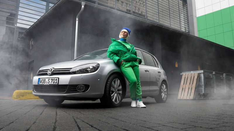 A woman leans against her VW Golf 6 with VW accessories