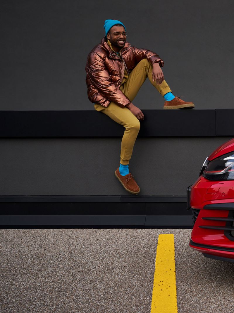 Un homme heureux à côté de sa Volkswagen Golf 7 rouge