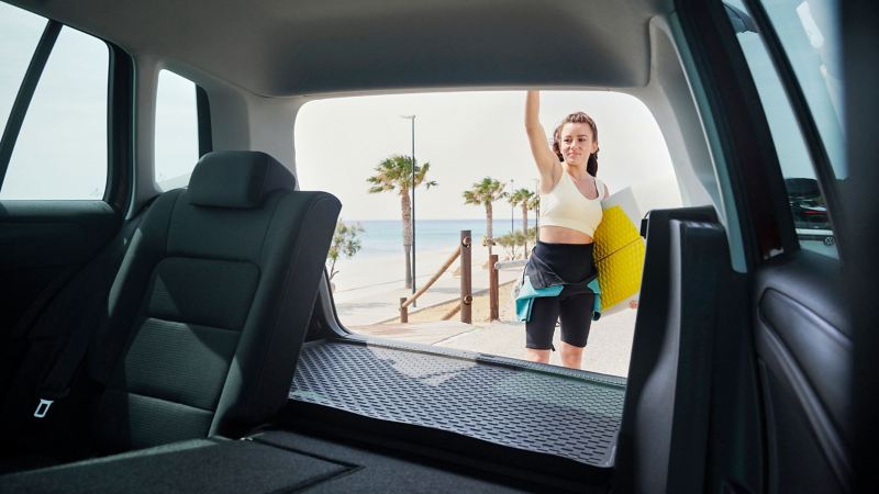 Eine Frau steht an der offenen Kofferraumklappe des VW Golf Sportsvan