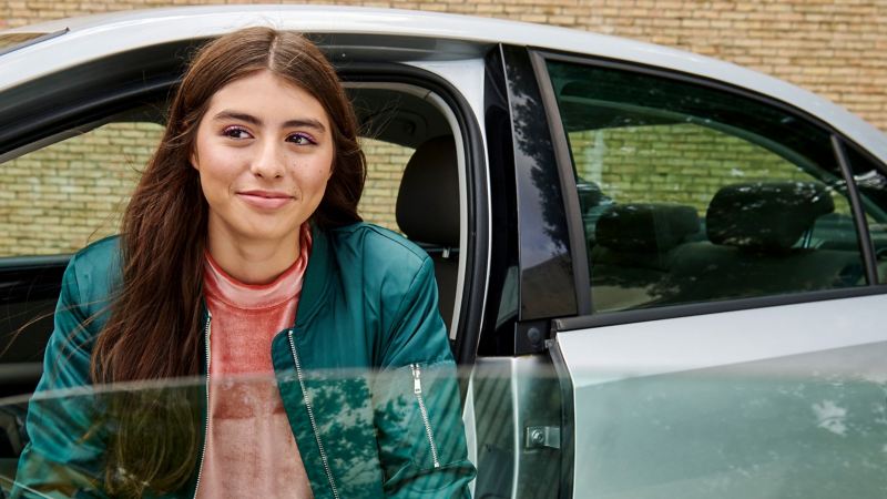 Woman in the driver's seat with the driver's door of a VW Jetta 6 open