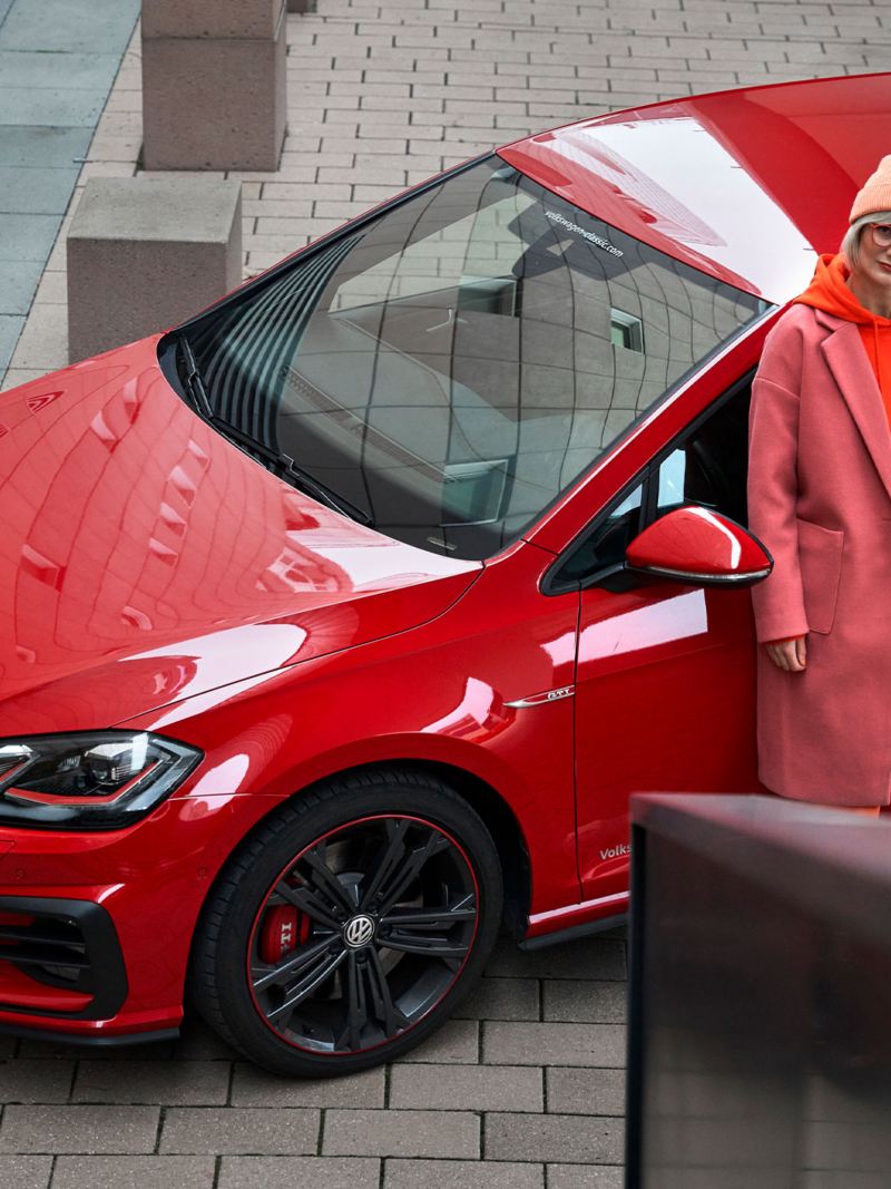 Eine Frau und ihr rotes Golf 7 VW Vorgängermodell