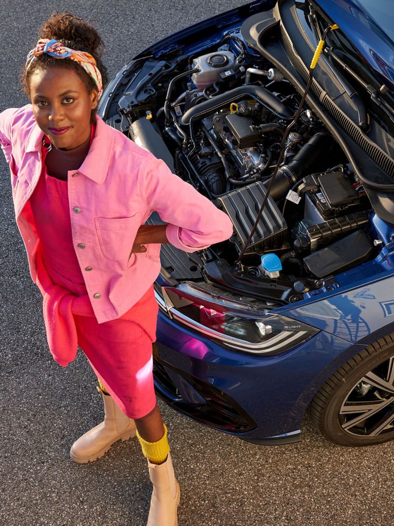 Eine Frau neben ihrem Volkswagen mit offener Motorhaube