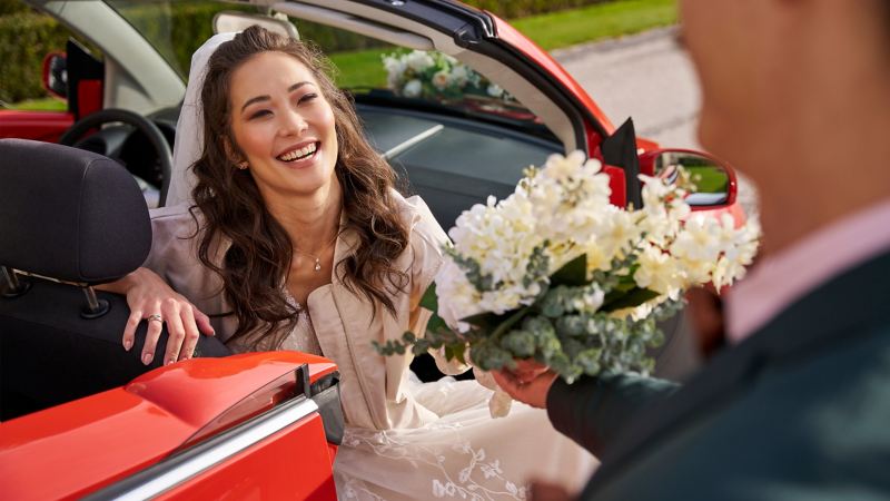 Bride in VW New Beetle receives bridal bouquet