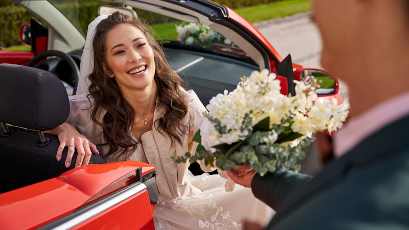 Una novia en un Volkswagen Beetle con un ramo de flores