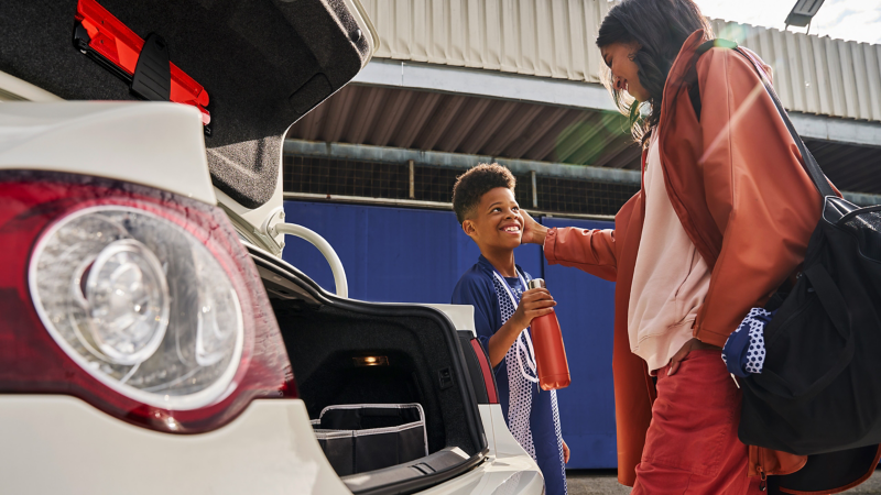 Une femme et un enfant à côté d’une VW Passat B6 avec le coffre ouvert