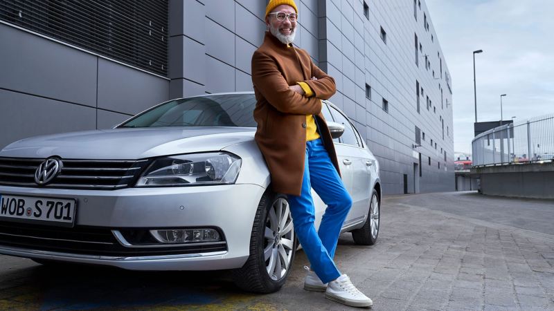 Un homme se tenant à côté de sa Volkswagen Passat B7 d’occasion