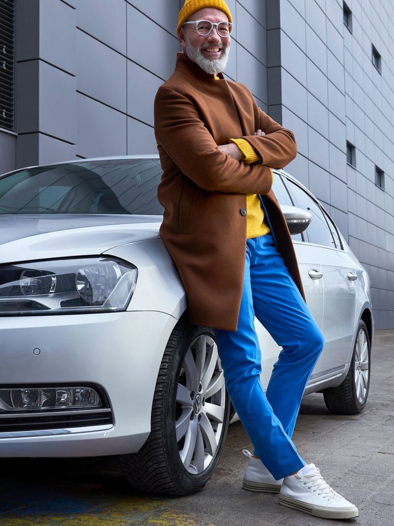 Un homme se tenant à côté de sa Volkswagen Passat B7 d’occasion