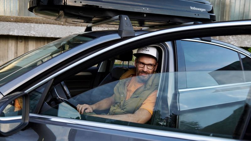 Man sitting in the driver's seat of a VW Passat B8, driver's door is open