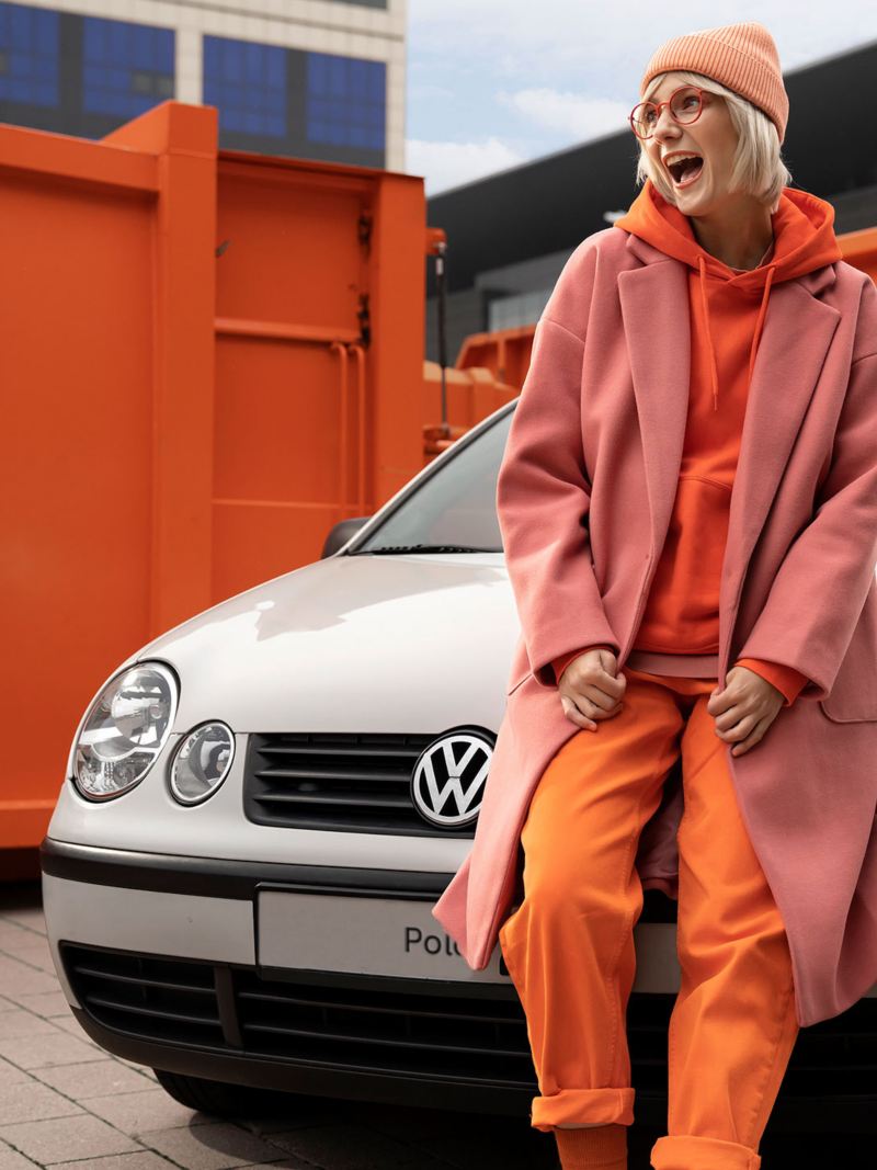 A woman leans against her used small car from Volkswagen