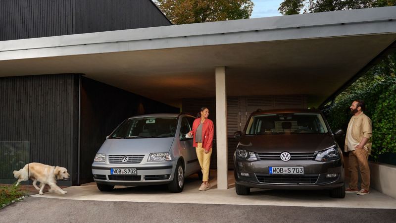 Paar mit Hund jeweils neben einem VW Vorgängermodell in der Garage