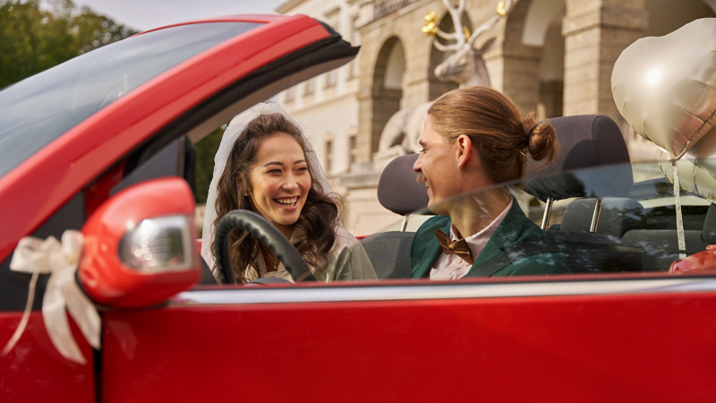 Couple de jeunes mariés dans un ancien modèle VW décoré pour l’occasion