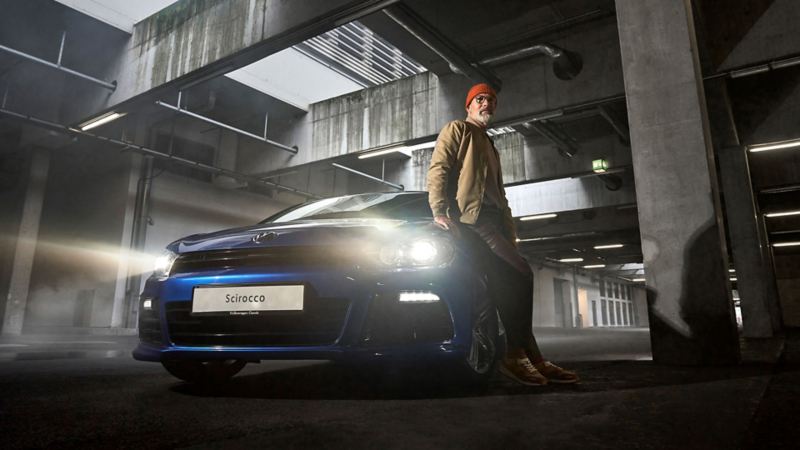 A man leans against his VW Scirocco 3 with VW accessories