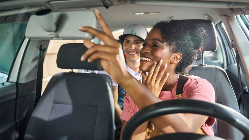 Woman looks through the interior mirror at her friend in the back seat