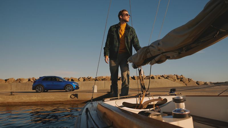 Ein Mann steht auf einem Boot, im Hintergrund parkt der VW T-Roc R