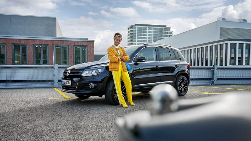 Kobieta w żółtym ubraniu opiera się o VW Tiguan 1