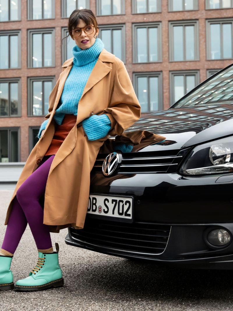Eine Frau lehnt sich an ihren Touran 1 von Volkswagen