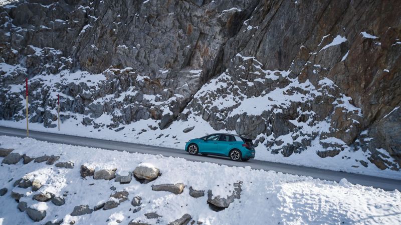 Une VW ID.3 roule le long d’un col de montagne enneigé – roues hiver complètes