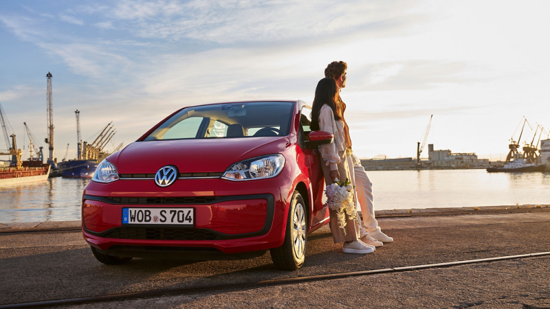 Man and woman leaning against VW up!, harbour basin in the background