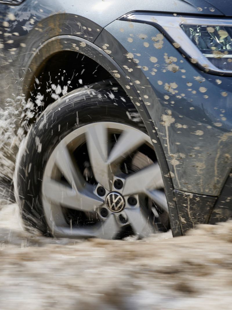VW car drives through mud and sludge, right front wheel in focus