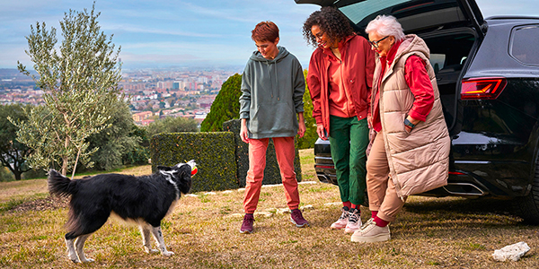 Famiglia felice con cane davanti al bagagliaio aperto di VW Touareg.