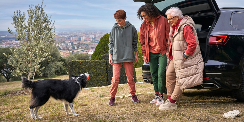 Glückliche Familie mit Hund vor geöffnetem Kofferraum eines VW Touareg